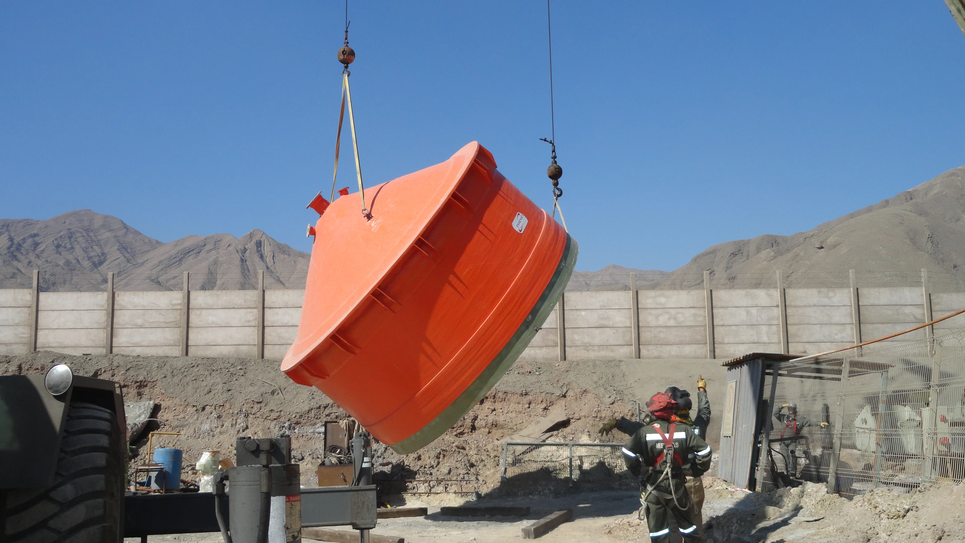 Crane lifting the FRP acid product tank in the plant yard, with workers on the ground.