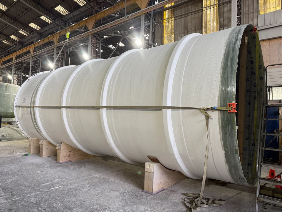 Estanque horizontal de gran formato en FRP, con bandas de refuerzo, apoyado sobre soportes dentro de una nave industrial.