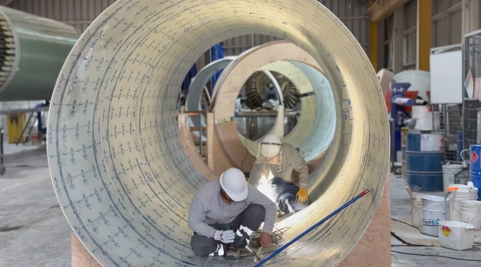 Interior view of a large-diameter FRP duct section, with workers performing tasks inside the piece.