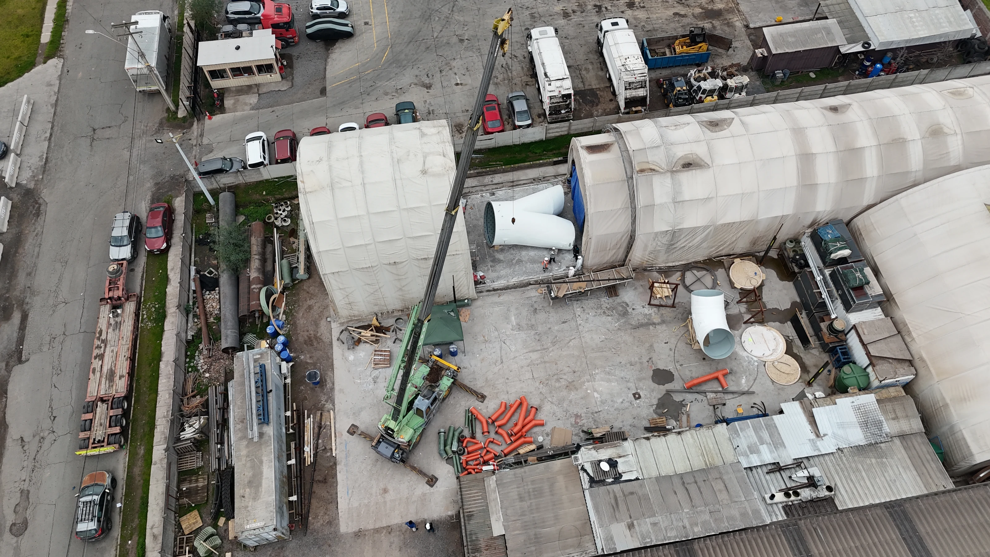 Aerial view of the plant yard, with a mobile crane, the fabrication tents and large-diameter pieces at different stages.