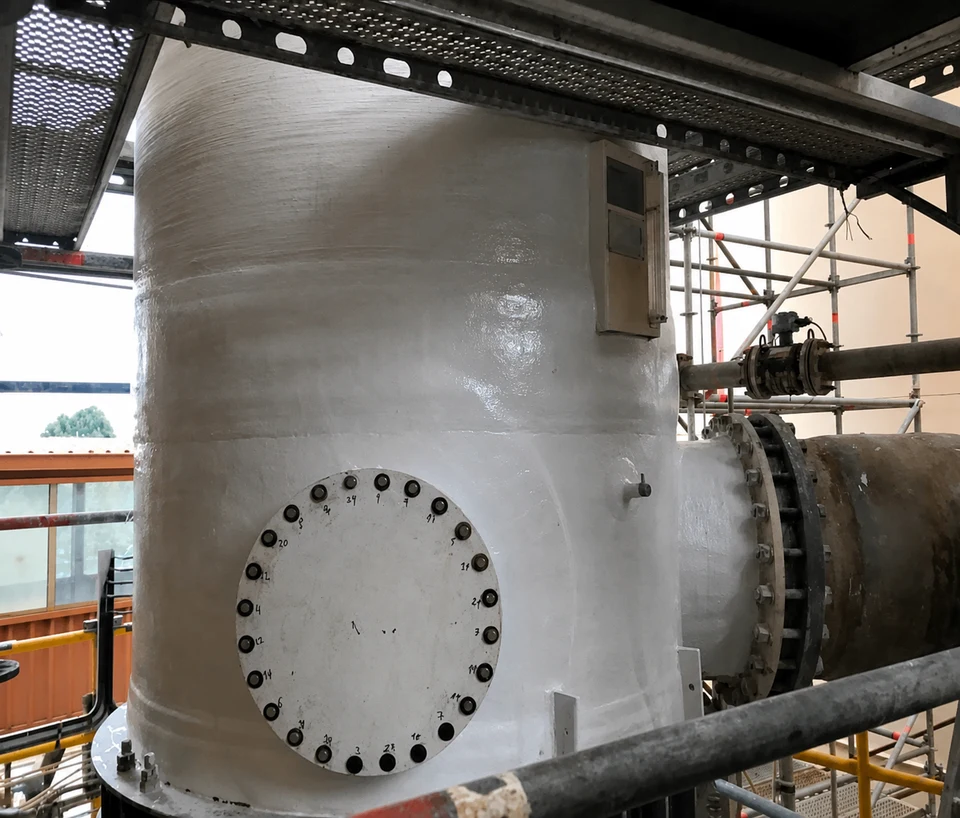 Cylindrical FRP body with a flanged nozzle and a bolted inspection cover, between scaffolding and walkways.