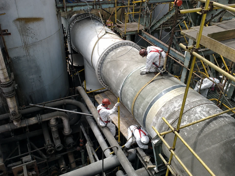 Workers performing work on an industrial duct in the field.