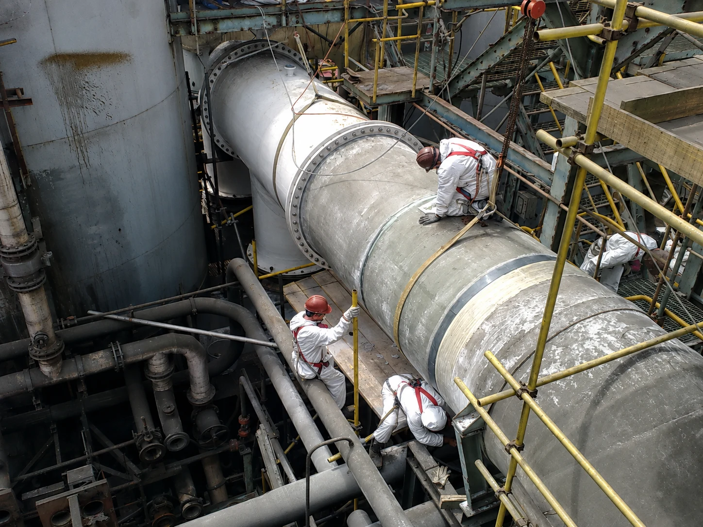 Workers performing work on an industrial duct in the field.