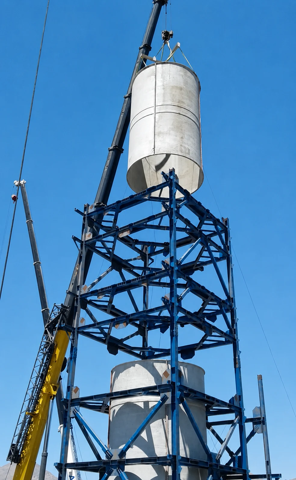 Cranes mounting a cylindrical body onto the steel structure of the desulfurization tower.
