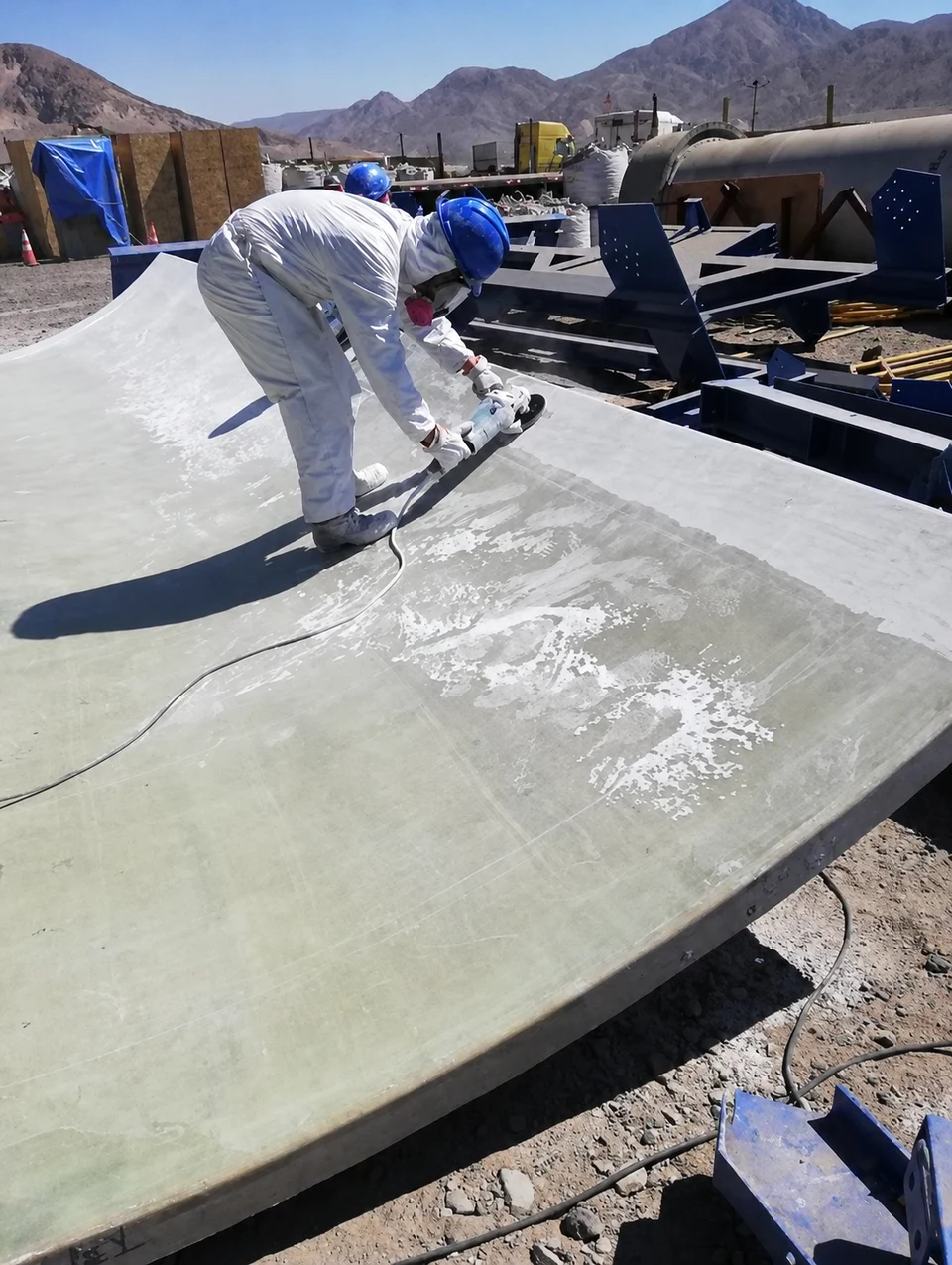 Worker finishing the surface of a curved FRP component in the field.