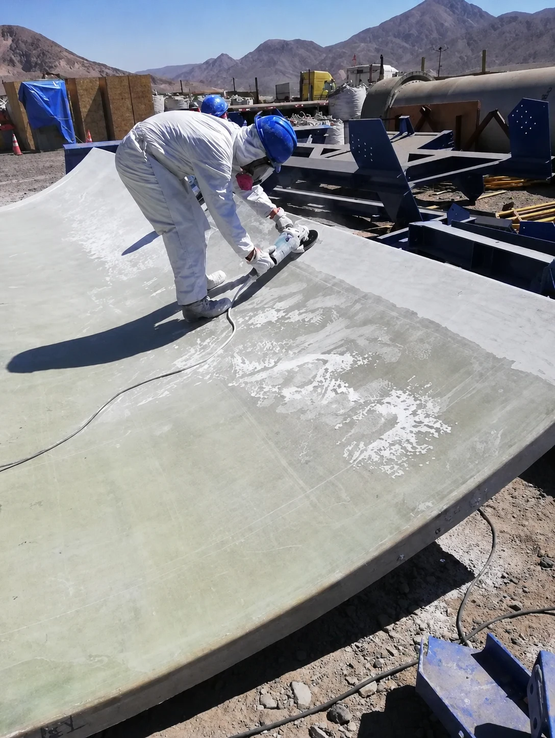 Worker finishing the surface of a curved FRP component in the field.